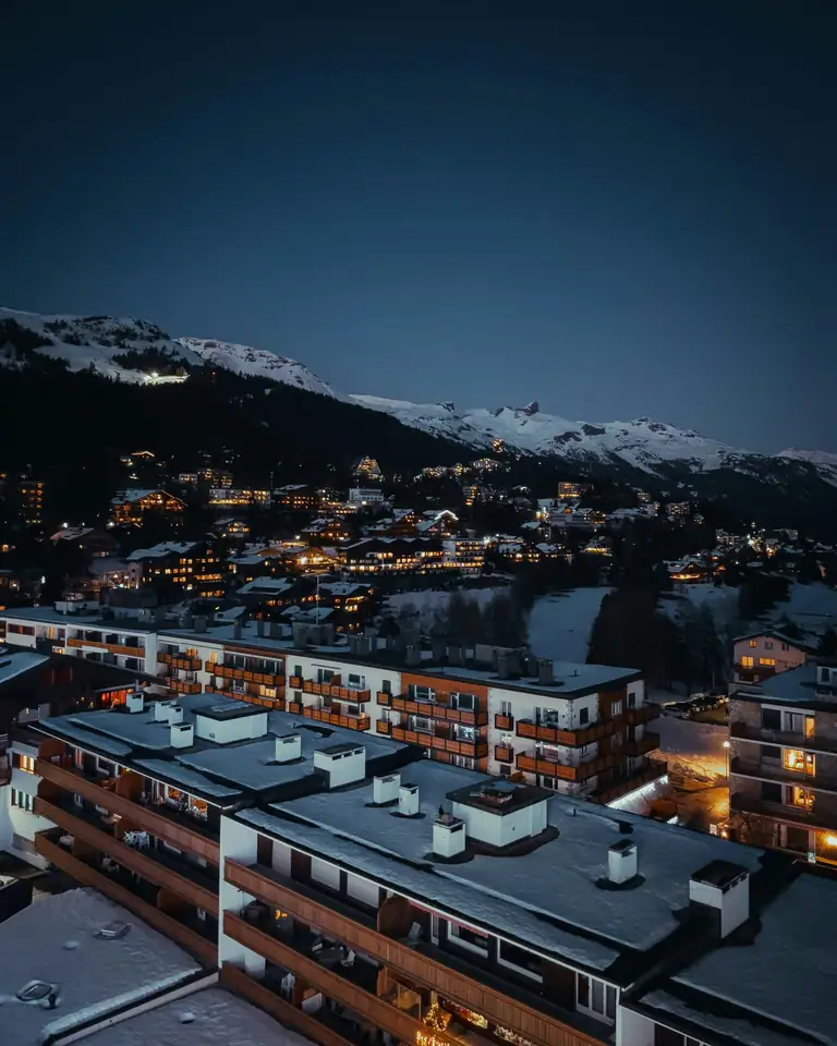 Alpine resort at night, lit chalets below snow-covered peaks