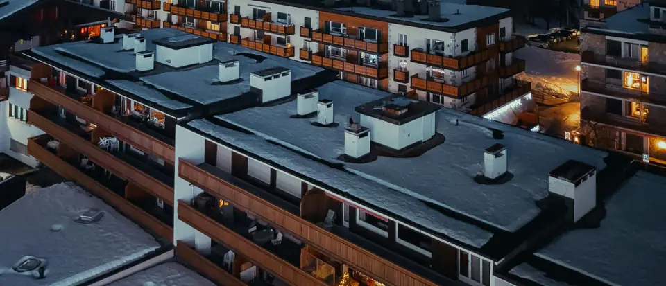 Snow-covered roofs and lit balconies of an alpine resort at night