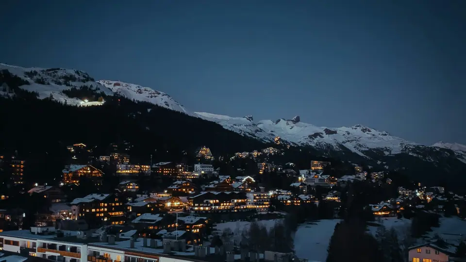 Alpine resort at night below snow-covered peaks